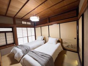 two twin beds in a room with windows at Tani House Tokiwa Nozawa Onsen & More in Iiyama +4 photos