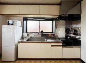 a kitchen with a sink and a white refrigerator at Tani House Tokiwa Nozawa Onsen & More in Iiyama