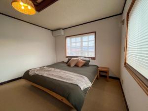 a bedroom with a bed in a room with a window at Tani House Tokiwa Nozawa Onsen & More in Iiyama