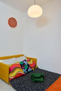 a couch with colorful blankets and a clock on the wall at 2 OG HbF Wuppertal DomusKushal in Wuppertal