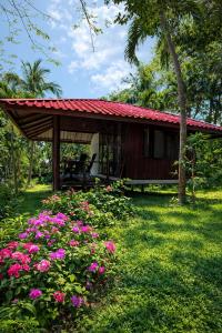 a small house with a red roof and pink flowers at Pankabay Resort in Ko Bulon Le