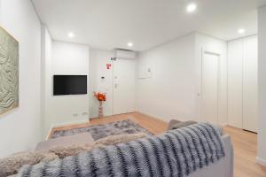 a living room with a couch and a tv on a wall at Leiria Boutique Apartment in Leiria