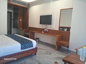 a bedroom with a bed and a desk with a television at KING'SWAY Hotel & Resort in Dūngarpur