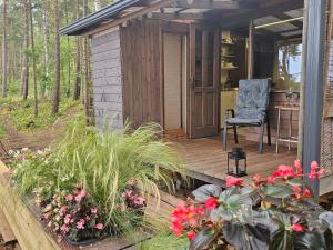 a small cabin with a chair on a wooden deck at Skaisto saulrietu namiņš in Lembuži +15 photos