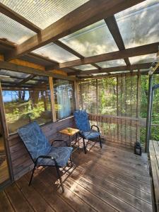 a screened in porch with two chairs and a table at Skaisto saulrietu namiņš in Lembuži