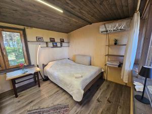 a small bedroom with a bed and a table at Skaisto saulrietu namiņš in Lembuži