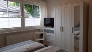a bedroom with a tv and a bed and windows at Ferienwohnung Sommerwind in Willingen