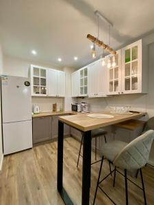 a kitchen with a table and a white refrigerator at Апартаменты CLASSIC в жк Империал in Truskavets