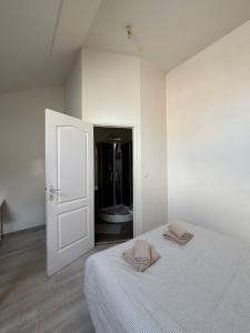 a white room with a bed with two towels on it at L'Aile de Fontainebleau in Fontainebleau