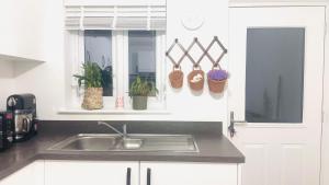 a kitchen with a sink and a window with plants at Gilded Nest-Room with Detached Bath- Ideal for ONE- WIFI, Car Parking-Shared House in Newarthill +3 photos