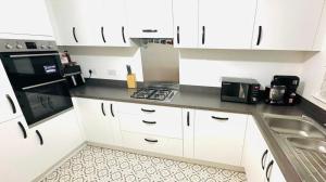 a kitchen with white cabinets and a stove top oven at Gilded Nest-Room with Detached Bath- Ideal for ONE- WIFI, Car Parking-Shared House in Newarthill