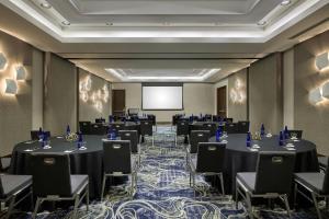 a conference room with tables and chairs and a screen at The Alexander, Autograph Collection in Indianapolis