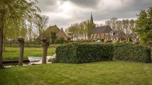 a hedge in front of a yard with a house at By de barte in Beers +3 photos