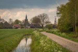 a country road in front of a church and a river at By de barte in Beers