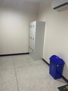 a room with a blue trash can next to a wall at Doctor Thanut Hostel in Ubon Ratchathani