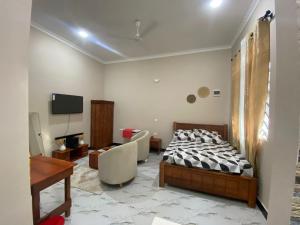 a bedroom with a bed and a couch and a television at Mnazinisky B&B in Zanzibar City