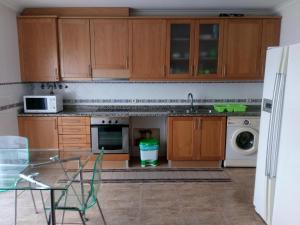 a kitchen with wooden cabinets and a sink and a dishwasher at House Victoria in Nazaré