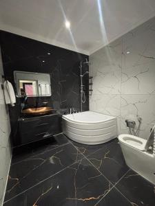 a black and white bathroom with a toilet and a sink at Grand Teatro Hotel in Ganja