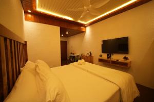 a bedroom with a white bed and a flat screen tv at Misty Garden Retreat in Nandigunda