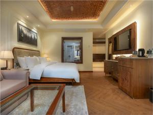 a bedroom with a bed and a couch and a tv at The Harmukh Hills in Batakūt