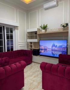 a living room with two red couches and a flat screen tv at Villa Bali Rice Field in Sukaraja