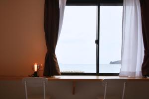 two chairs in front of a window with a view of the ocean at シーサイド興津 in Sanuki