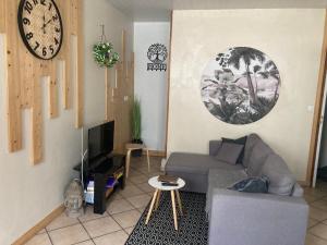 a living room with a couch and a clock on the wall at Olivine , Chaleureuse & cocooning in Bogny Sur Meuse