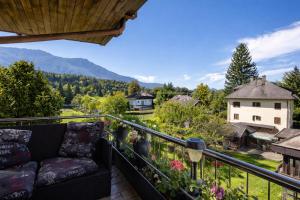 a couch on a balcony with mountains in the background at Apartment Auszeit nahe Faaker See 24h Self Check-in in Latschach