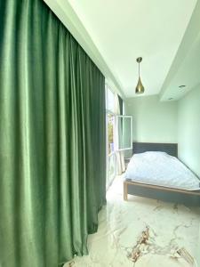 a bedroom with a bed and a green curtain at Apartamenti Panorama in Kobuleti