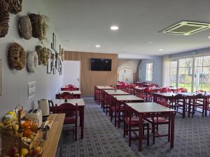 a dining room with tables and chairs and a tv at Hotel Saint Odilon in Cluny
