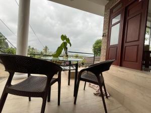 a glass table and chairs on a porch with a plant at Cottage Fifty One in Kandy