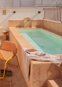 a large swimming pool with a chair and a chair at LIRIUM Casa Patio in Seville