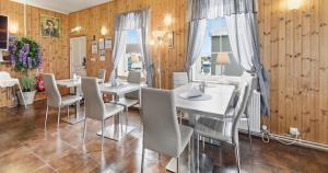 a dining room with white tables and chairs and wooden walls at Guesthouse Kiljan in Blönduós