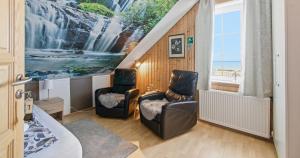 a bedroom with two chairs and a painting on the wall at Guesthouse Kiljan in Blönduós