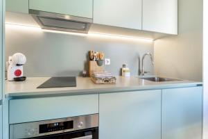 a kitchen with white cabinets and a sink at Castle Boutique Studio in Leiria