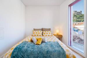 a bedroom with a bed with yellow pillows and a window at Castle Boutique Studio in Leiria