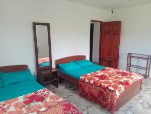 a room with two beds and a mirror at Oneli Homestay in Nuwara Eliya