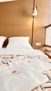 a bed with white sheets and a lamp on it at Лофт отель 11eleven in Shymkent +5 photos