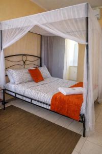 a bedroom with a canopy bed with an orange blanket at Kabula Lodge in Blantyre