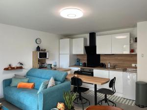 a living room with a blue couch and a kitchen at L'Appart'CASANELLA in Sarzeau