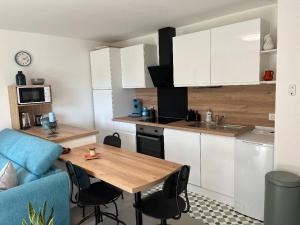 a kitchen with a wooden table and a blue couch at L'Appart'CASANELLA in Sarzeau +2 photos