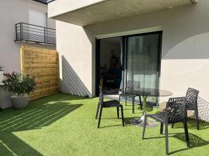 a patio with a table and chairs on the grass at L'Appart'CASANELLA in Sarzeau