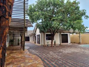 a brick driveway in front of a building with trees at Wild Haven Lodge in Victoria Falls