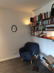 a blue chair in a room with a shelf of books at Zonnehoek in Bruinisse