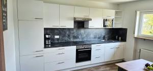 a kitchen with white cabinets and a black counter top at Ferienwohnung Rütschlin in Nollingen