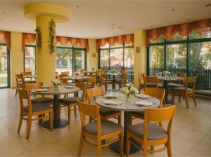 a restaurant with tables and chairs and windows at Hotel Perunika in Golden Sands