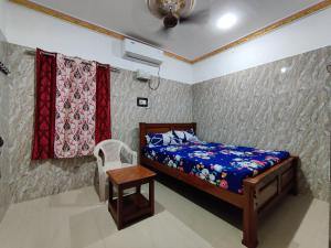 a bedroom with a bed and a chair and curtains at Siva Lodge in Rāmeswaram