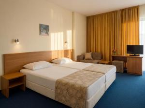 a hotel room with a large bed and a chair at Hotel Perunika in Golden Sands