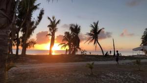 a sunset on a beach with palm trees at snowwhite castle hotel in Garapan