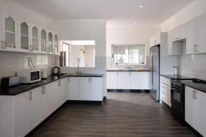a large white kitchen with white cabinets and black appliances at Kabula Lodge in Blantyre